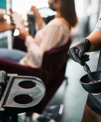 Close-up of hairstylist mixing hair dye while working at the salon. Close-up of hairstylist mixing hair dye while working at the salon.